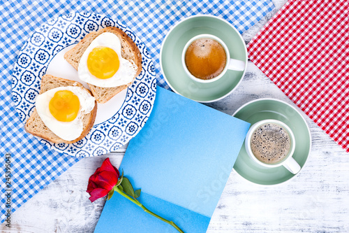 Flowers, Two cups of aromatic coffee and heart-shaped toasts for a romantic morning of lovers. Red rose, letter or note on the table. The concept of Valentine's Day and Mother's Day. Flat lay.   photo