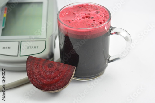 Beetroot juice with blood pressure machine on white background