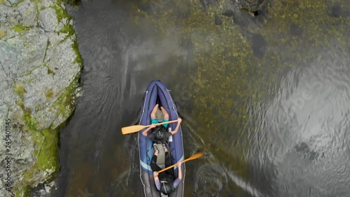 Children paddle blue inflatable canoe on river Pelorus river, New Zealand with boulder rocks - Top Down Aerial Drone photo