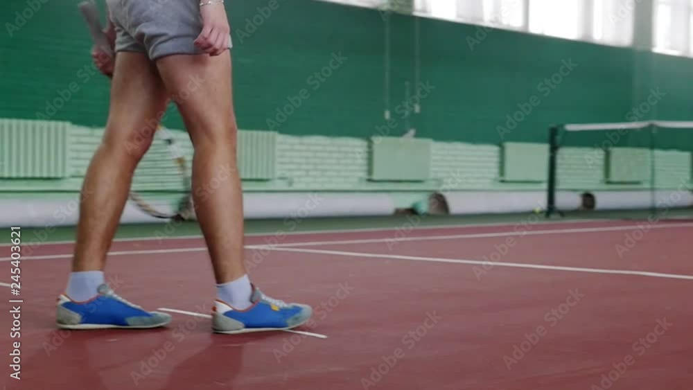 Training on the tennis court. Young man player walking on tennis court Training on the tennis court. Young man player walking on tennis court