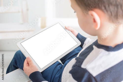 Kid play game on tablet in horizontal position. Isolated screen for mockup, app presentation. View behind shoulder. photo