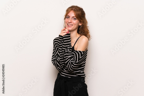 Young redhead woman over white wall smiling with a sweet expression © luismolinero