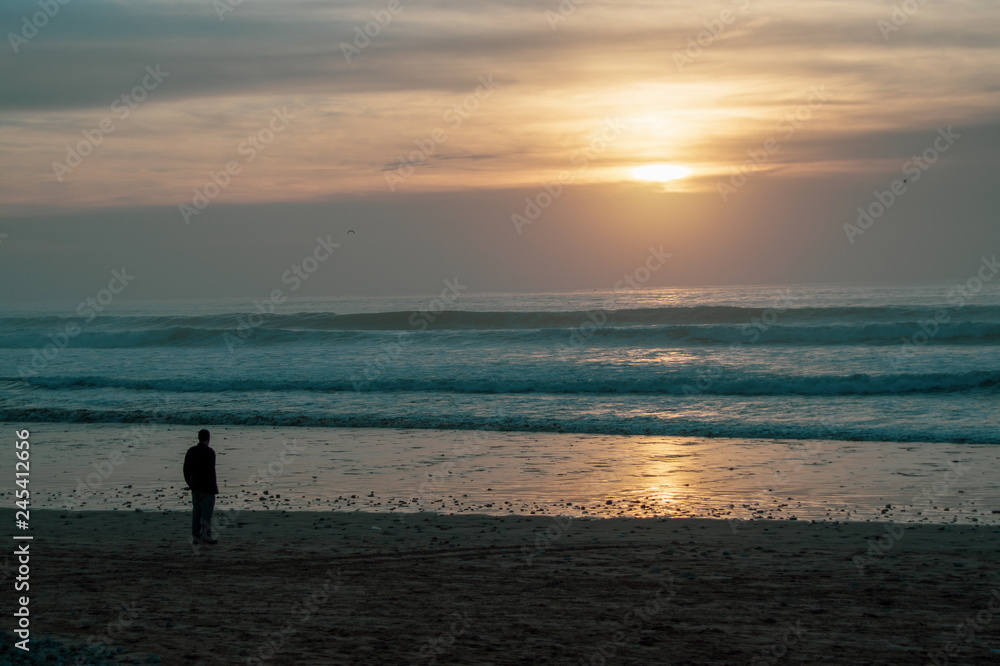 Sunset on the Main Beach at Agadir Morocco with people silhouetted while playing, fishing and surfing in waves