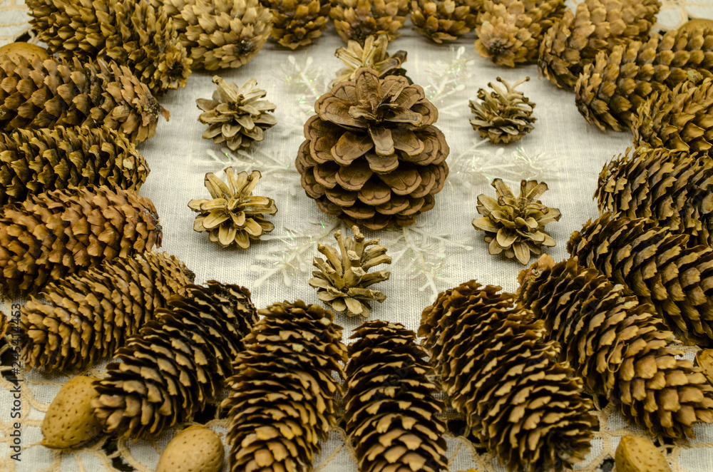 Fototapeta premium Embroidered white wavy napkin with a pattern of cones of different breeds, snowflakes and almonds along the edges of the pattern on a black background 