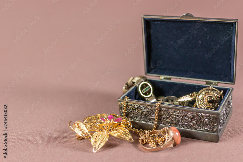 Small metal old style jewel case with jewellery on soft background