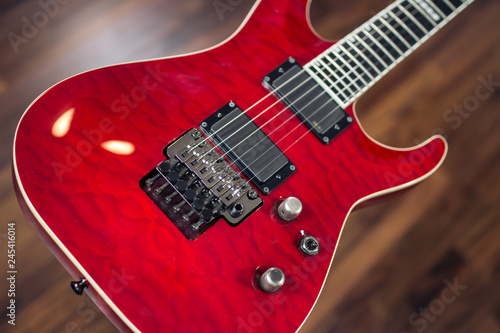 Electric guitar, red colour close up with wooden soft background