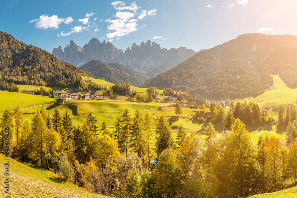 Famous travel destination in Italian Dolomites Funes valley. Val Di Funes and Santa Magdalena village during autumn with rocky Alps at the background