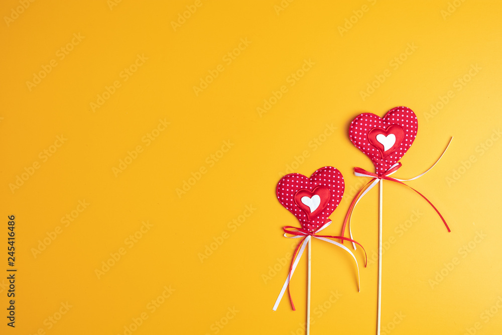 Two handmade hearts on yellow surface