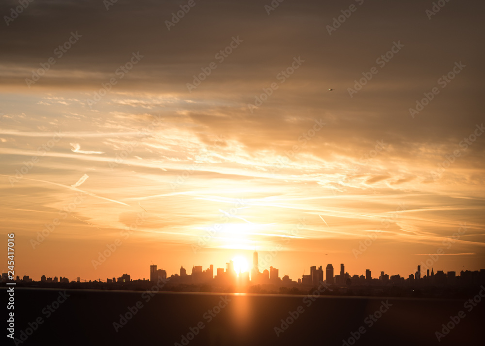 Bold glowing sunset over New York city skyline with clouds and contrails