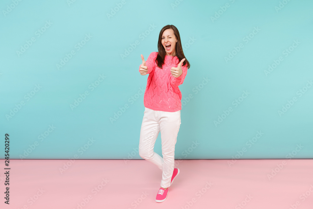 Full length portrait of smiling young woman in knitted rose sweater, white pants posing isolated on bright pink blue pastel wall background in studio. Fashion lifestyle concept. Mock up copy space. Full length portrait of smiling young woman in knitted rose sweater, white pants posing isolated on bright pink blue pastel wall background in studio. Fashion lifestyle concept. Mock up copy space.