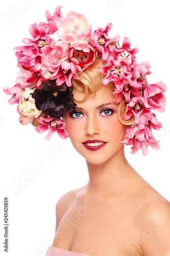 Young beautiful smiling girl with fancy make-up and colorful flowers in her hair over white background