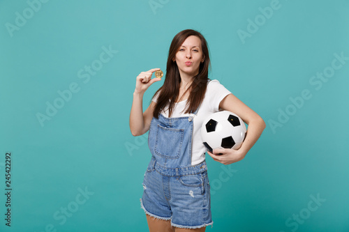 Funny girl football fan support favorite team with soccer ball, bitcoin future currency blowing air kiss isolated on blue turquoise background. People emotions, sport family leisure lifestyle concept. © ViDi Studio