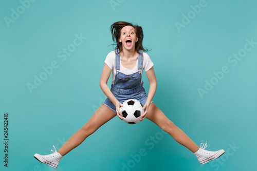 Dizzy woman football fan cheer up support favorite team holding soccer ball jumping isolated on blue turquoise background. People emotions, sport family leisure lifestyle concept. Mock up copy space. photo