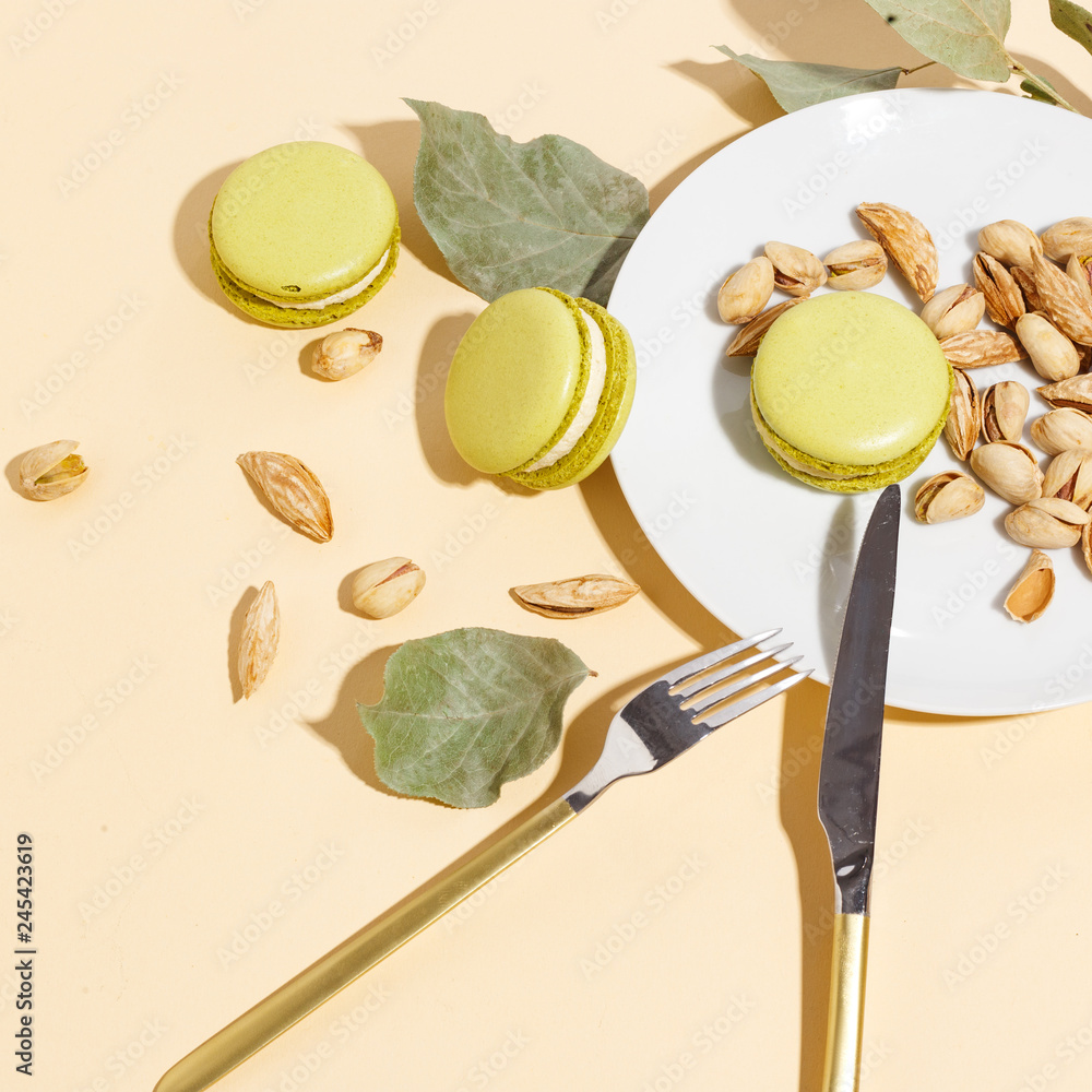 Pistachio cake makaroons and pistachios on a beige background. Top view. Pistachio cake makaroons and pistachios on a beige background. Top view.