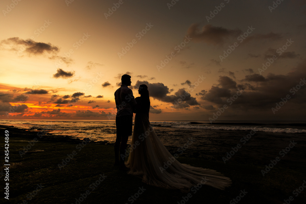 Bride and groom hugging on the beach at sunset Bride and groom hugging on the beach at sunset