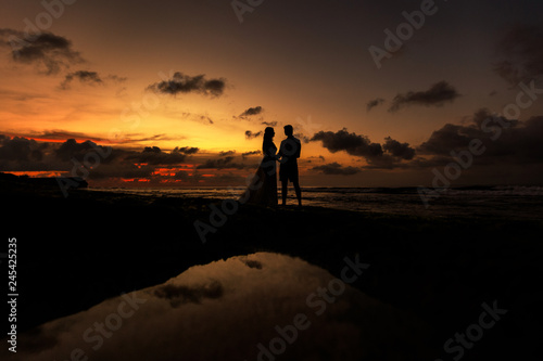 Silhouettes of the bride and groom on the beach at sunset
