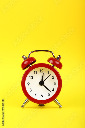 Close up one red alarm clock over yellow background