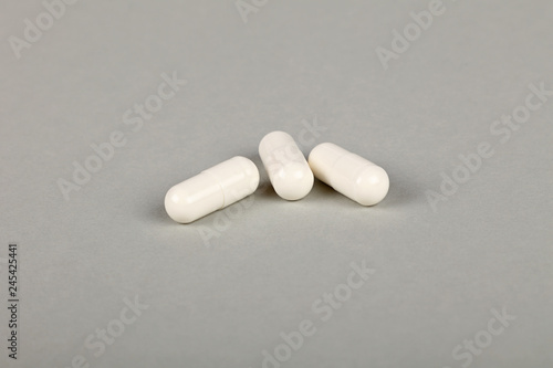 Close up three gel cap pills over grey background