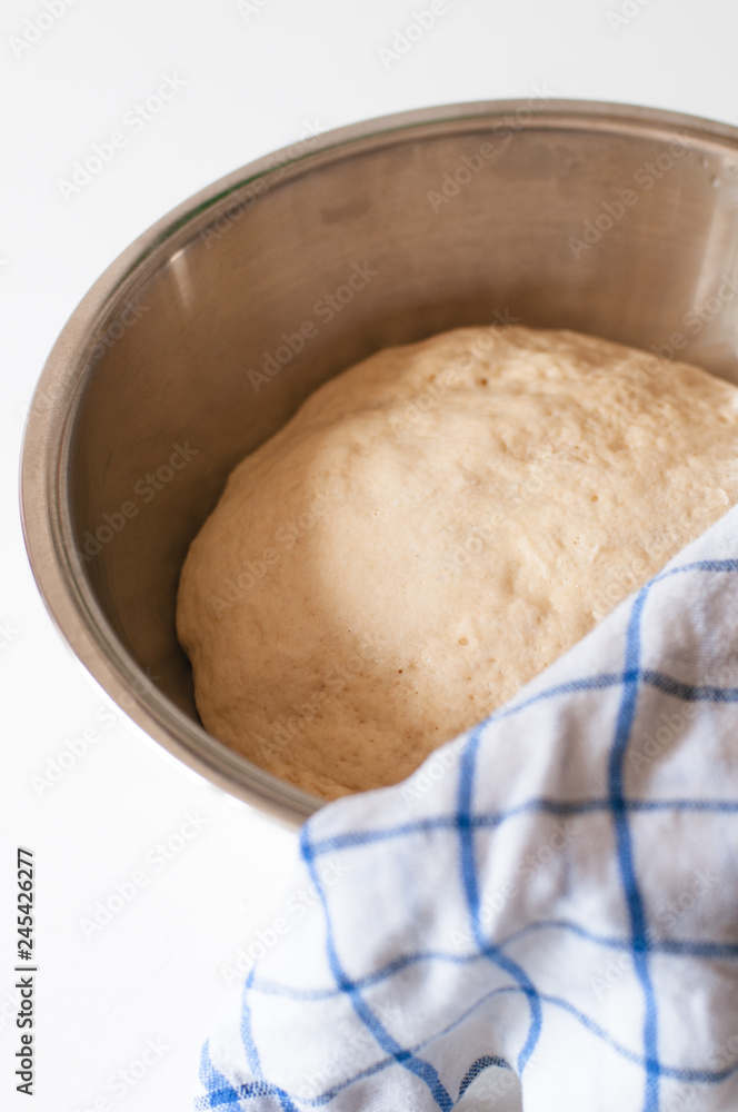 Yeast and white wheat flour dough after rising in bowl for homemade traditional German Kaiser rolls or Austrian Vienna rolls on white wooden background Yeast and white wheat flour dough after rising in bowl for homemade traditional German Kaiser rolls or Austrian Vienna rolls on white wooden background