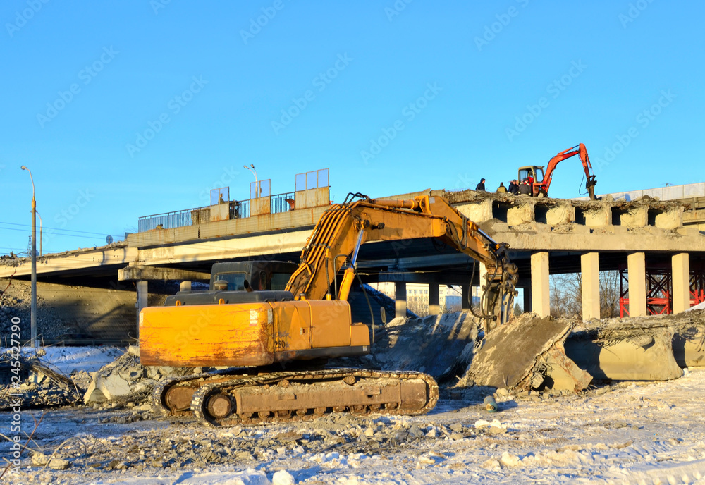 Excavator hydraulic crushes concrete slabs. Heavy construction equipment. Hydraulic breaker piles concrete and reinforcement pile elements into the ground and processes high-strength material