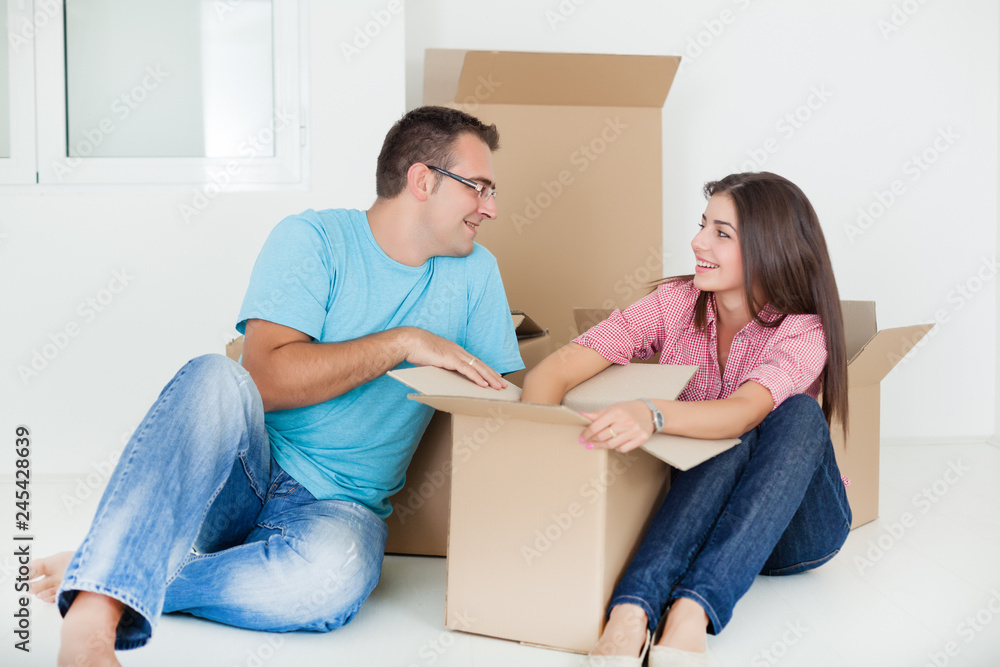 Portrait of beautiful,smiling woman sitting with man while unpacking cardboard boxes in new home Portrait of beautiful,smiling woman sitting with man while unpacking cardboard boxes in new home