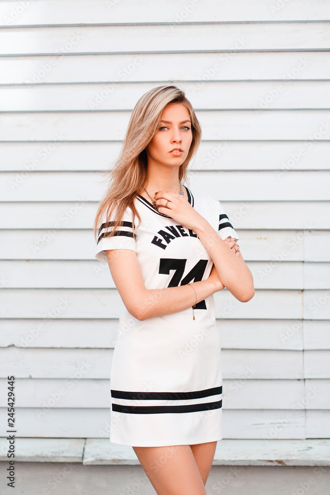 Stylish cute young woman in trendy summer dress posing outdoors