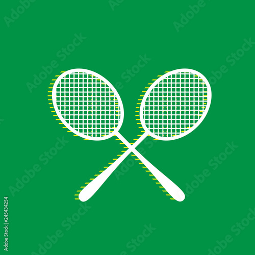 Two tennis racket sign. Vector. White flat icon with yellow striped shadow at green background. Illustration.