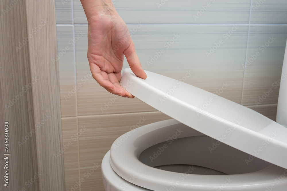 The hand closes or opens the toilet lid Stock Photo Adobe Stock