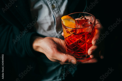 Negroni cocktail in men's hands close-up on dark background photo