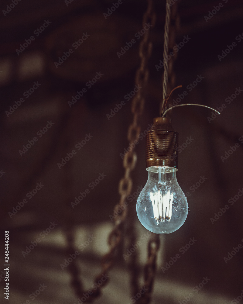 Old dusty light bulb glowing in the dark. 