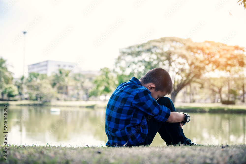 Little asian child sitting and waiting someone at frontwater. Depressed asian boy. Young asian boy sad Little asian child sitting and waiting someone at frontwater. Depressed asian boy. Young asian boy sad