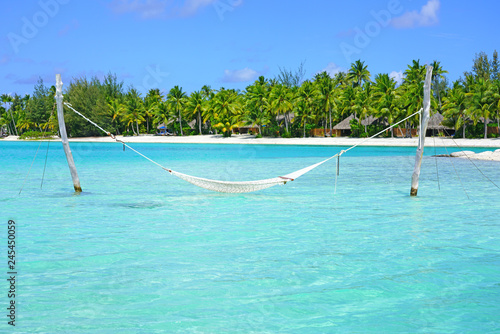Hammock with a view, planted in the azure waters of the Bora Bora lagoon, French Polynesia 