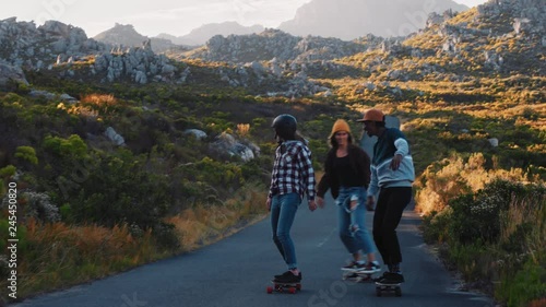 happy multi ethnic friends longboarding together riding skateboard cruising on countryside road having fun hanging out enjoying relaxed summer vacation photo