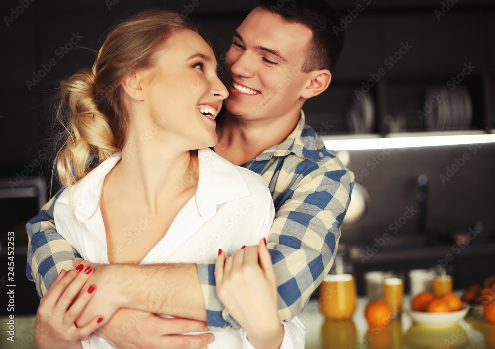 Lovely young couple standing and hugging on a kitchen at home Lovely young couple standing and hugging on a kitchen at home