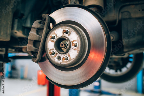 Close up of car disc brake during the wheel tire change or repair. Disc brake of the car during the maintenance at auto service garage.  photo