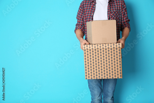 Man with moving boxes on color background. Space for text