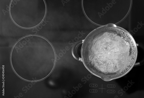 Fotografie Pot with boiling water on stove, top view. Space for text
