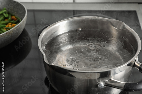 Pot with boiling water on electric stove, closeup