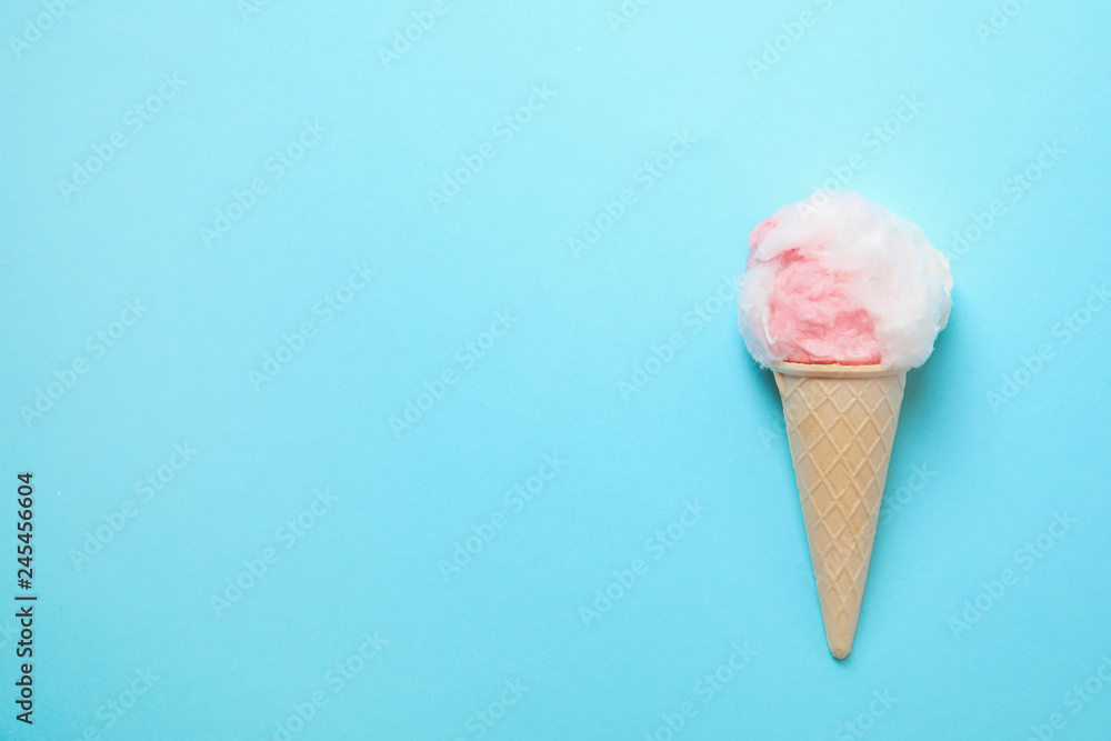 Ice cream cone with fluffy cotton candy and space for text on color background, top view Ice cream cone with fluffy cotton candy and space for text on color background, top view
