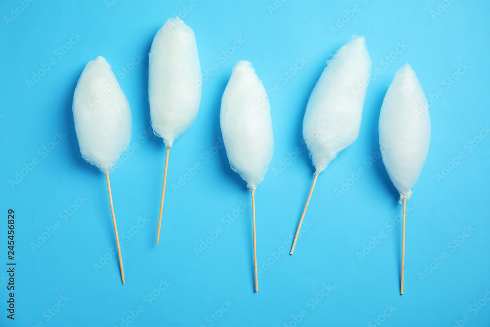 Sticks with yummy cotton candy on color background, top view Sticks with yummy cotton candy on color background, top view