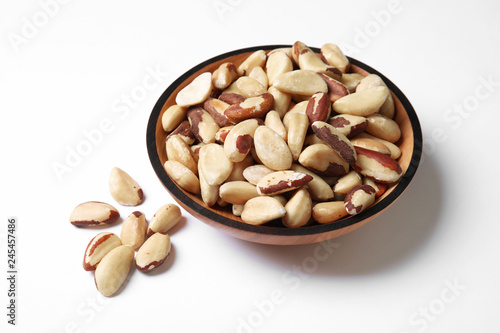 Wooden bowl with Brazil nuts on white background © New Africa