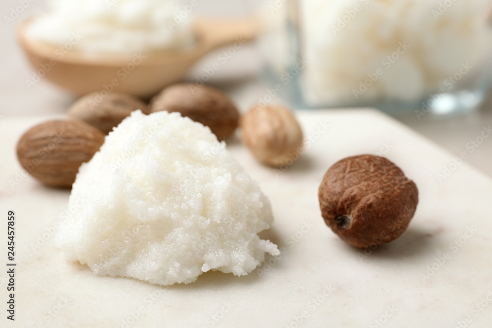 Fototapeta premium Shea butter and nuts on marble board, closeup