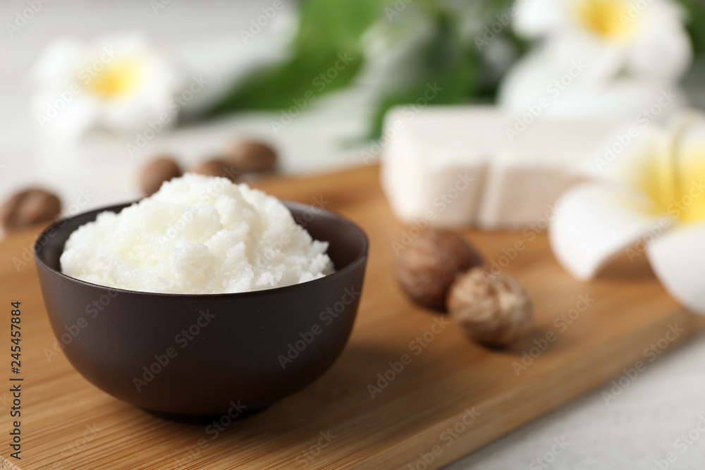 Shea butter in bowl and nuts on wooden board, closeup. Space for text Shea butter in bowl and nuts on wooden board, closeup. Space for text