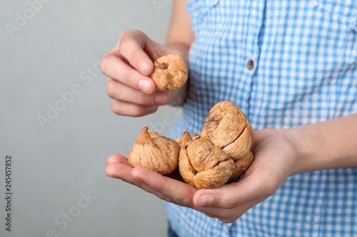 Woman holding handful of dried figs on light background, space for text. Healthy fruit