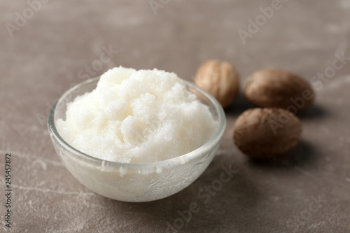 Fototapeta Naklejka Na Ścianę i Meble -  Shea butter in bowl and nuts on grey background, closeup