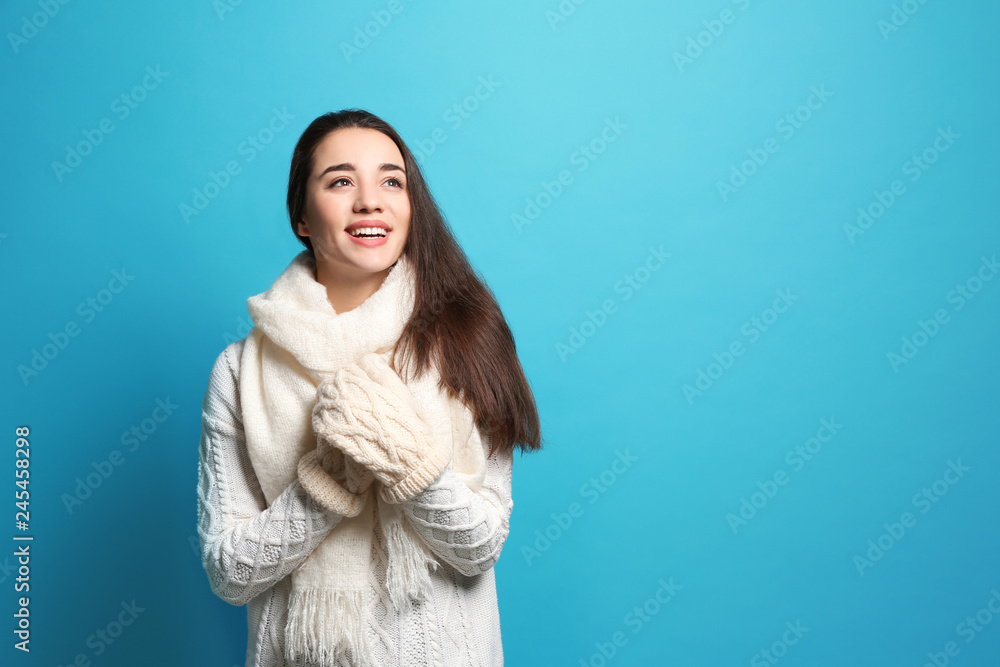 Young woman wearing warm clothes on color background, space for text. Winter season Young woman wearing warm clothes on color background, space for text. Winter season