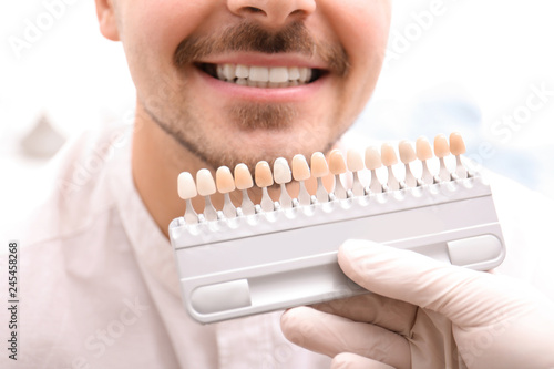 Dentist checking young man's teeth color, closeup