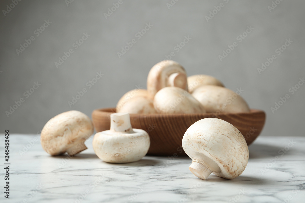 Fresh champignon mushrooms on marble table, space for text