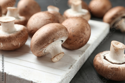 Fresh champignon mushrooms on wooden cutting board, closeup