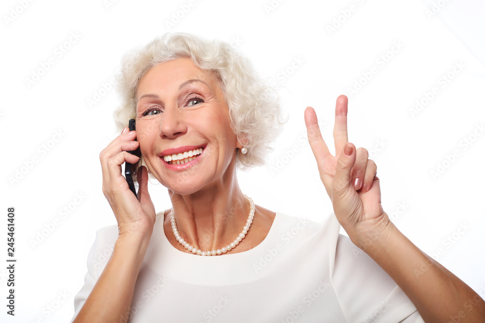 lifestyle, tehnology and people concept: Elderly lady holding a smartphone making v-sign lifestyle, tehnology and people concept: Elderly lady holding a smartphone making v-sign